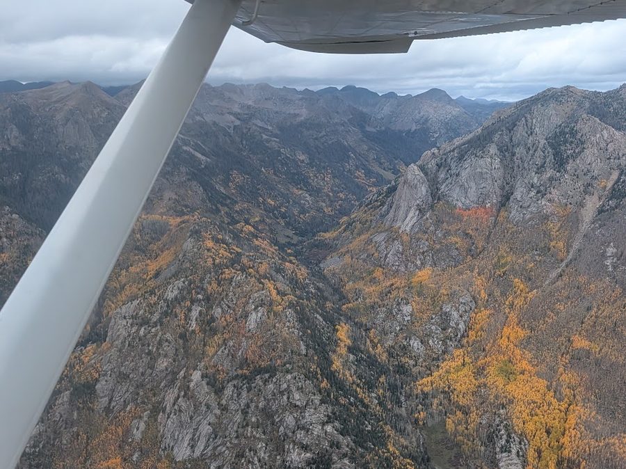 View from under a wing of a steep canyon with fall aspens